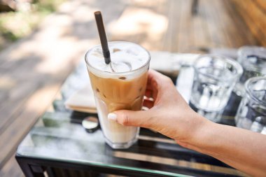 Bir bardak buzlu soğuk kapuçino. Kahve dükkanının ortak çalışma alanındaki masa. Güneşli bir günde verandada bir fincan kahve. Kafede kahve molası. Yakın plan. Yüksek kalite fotoğraf.