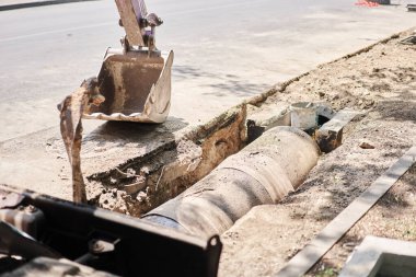 Büyük matkap matkabı yolu. Ağır makineler, fırtına suyu giderlerini onarmak için asfaltı eziyor. Kazı makinesi suda izler bırakmış. Bir yolun tamiri ve genişletilmesi. Yüksek kalite fotoğraf