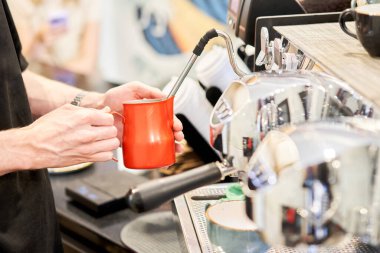 Barista kahve fincanına krema döker. Küçük bir kahve dükkanı. Profesyonel bir barista keçiboynuzu kahve makinesinde kahve hazırlar. Restoran sektöründe en sevdiği iş. Yüksek kalite fotoğraf