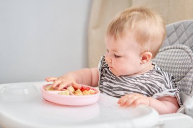 Şirin çocuk sağlıklı sebzeler ve buharda pişirilmiş et köfteleri yiyor. 10 aylık güzel bir kızın portreleri. Bebek bebekler için özel bir sandalyede oturuyor. Yüksek kalite fotoğraf