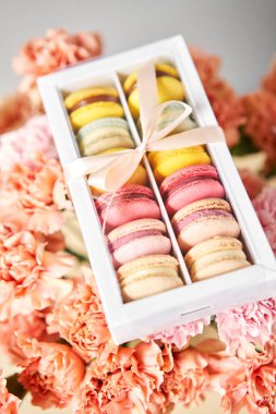 Mevcut kutuda Fransız makarnası var. Çiçek arkaplanda tatlı bir tatlı. Makarna kekleri ve farklı çiçeklerle dolu bir hayat. Teslimat konsepti, kahve ve çiçekçi. Yüksek kalite fotoğraf