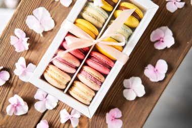 Mevcut kutuda Fransız makarnası var. Çiçek arkaplanda tatlı bir tatlı. Makarna kekleri ve farklı çiçeklerle dolu bir hayat. Teslimat konsepti, kahve ve çiçekçi. Yüksek kalite fotoğraf