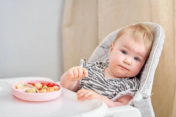 Cute child eats healthy food vegetables and meatballs from dietary meat steamed,. Portraits of a cute 10 months old baby girl. The baby sitting in a special high chair for babies. High quality photo