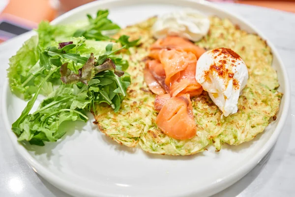 stock image  Girl cuts poached egg and yolk flows out. Potato waffles, avocado cream with salmon and egg . Healthy breakfast, protein. Restaurant dish. Stop Motion