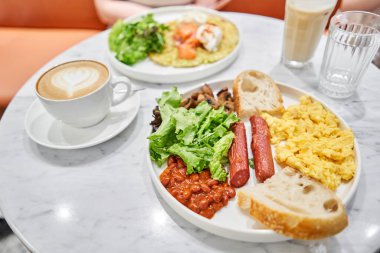 Sade Amerikan usulü sosisli kahvaltı, çırpılmış yumurta, fırında fasulye, mantar ve domates. Bu yemek ihtiyacın olan besinlerle dolu. Yüksek kalite fotoğraf
