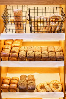 Pastanedeki tezgahın üzerinde farklı türde ekmek var. Taze ekmek tezgahı. Farklı ekmek, kek ve çörekleri olan modern bir fırın. Yüksek kalite fotoğraf