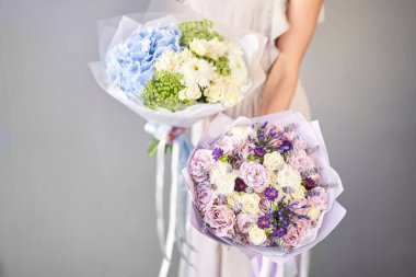 İki küçük güzel buket karışık çiçek kadının elinde. Çiçek dükkanı konsepti. Taze kesilmiş güzel bir buket. Çiçek teslimatı. Yüksek kalite fotoğraf