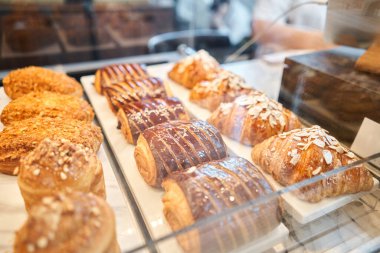 Pastanenin vitrininde çeşitli taze hamur işleri var. Bademli kruvasan bir kafede diğer hamur işlerinin yanında taze ve sıcaktır. Bir İtalyan restoranının içi. Yüksek kalite fotoğraf