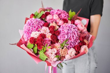 Kadının elinde küçük, güzel bir buket karışık çiçek. Çiçek dükkanı konsepti. Taze kesilmiş güzel bir buket. Çiçek teslimatı. Yüksek kalite fotoğraf