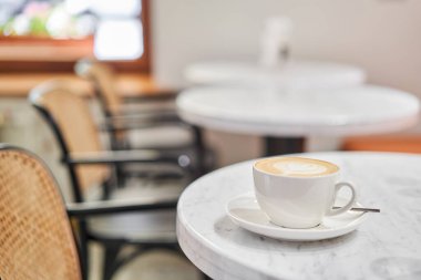 Kahve dükkanının çalışma alanındaki masanın üzerinde bir fincan sıcak kapuçino. Güneşli bir günde verandada bir fincan kahve. Kafede kahve molası. Yakın plan. Yüksek kalite fotoğraf.