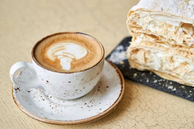 Kafede kahvaltı, sabah kahvesi. Kapuçino ve Napolyon tatlısı masada. Yüksek kalite fotoğraf