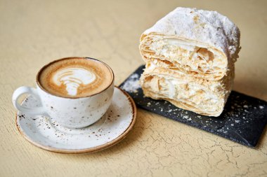 Kafede kahvaltı, sabah kahvesi. Kapuçino ve Napolyon tatlısı masada. Yüksek kalite fotoğraf