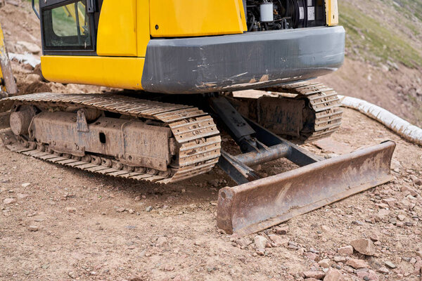 Экскаватор работает в горах. Делает траншею для связи. вода и электричество. в ущелье гор. ремонт и расширение дороги. Высокое качество фото