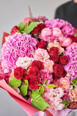 Kadının elinde küçük, güzel bir buket karışık çiçek. Çiçek dükkanı konsepti. Taze kesilmiş güzel bir buket. Çiçek teslimatı. Yüksek kalite fotoğraf