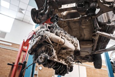 Bir araba tamircisi el feneriyle motoru inceliyor. Motor bloğu, özel vinç krikosuyla birlikte tamir masasında. Araba için teknik servis istasyonu yüksek kaliteli fotoğraf.