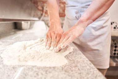 Şef pizza hazırlar. Çiğ pizza pişirmeye hazır. Mutfakta önlüklü aşçı pizza hamuru yapıyor. Arka planda yiyecek teslimatı için kutular. neopolitan