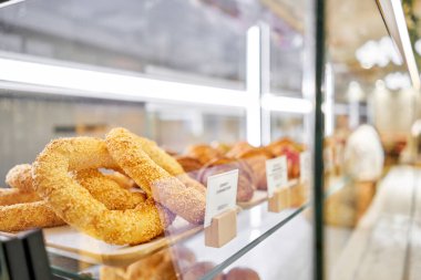 Ön plandaki Bun Simit. Birçok kruvasan, diğer hamur işlerinin yanında bir kafede taze ve sıcaktır. Pastanenin vitrininde çeşitli taze hamur işleri var. Bir İtalyan restoranının içi.