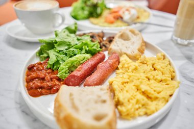 Sade Amerikan usulü sosisli kahvaltı, çırpılmış yumurta, fırında fasulye, mantar ve domates. Bu yemek ihtiyacın olan besinlerle dolu. Yüksek kalite fotoğraf