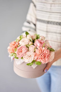 Çiçekçi kadın yuvarlak bir kutuda çiçek aranjmanı yapıyor. Güzel bir buket karışık çiçek. Çiçek dükkanı konsepti. Yakışıklılar. Çiçek teslimatı. Yüksek kalite fotoğraf