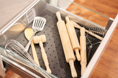 Kitchen utensil cutlery drawer organizer tray with simple set of tools, minimalist order. Open drawer with different utensils and folded towels. Order in kitchen. Kitchen furniture store. High quality