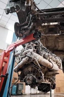 Bir araba tamircisi el feneriyle motoru inceliyor. Motor bloğu, özel vinç krikosuyla birlikte tamir masasında. Araba için teknik servis istasyonu yüksek kaliteli fotoğraf.