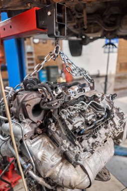 Bir araba tamircisi el feneriyle motoru inceliyor. Motor bloğu, özel vinç krikosuyla birlikte tamir masasında. Araba için teknik servis istasyonu yüksek kaliteli fotoğraf.
