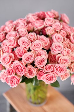 Çalı güllü cam vazo. Çiçeklerle çiçekçi ilgileniyor. Elinde bir vazo çiçek olan bir kız yüksek kaliteli bir fotoğraf.