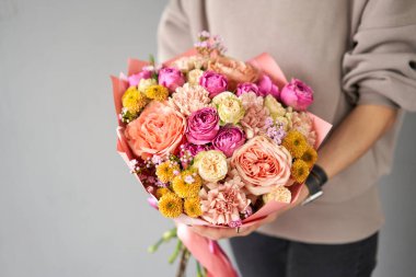 Dekor ambalajında güzel bir buket karışık çiçek. Kadın elinde güzel, taze bir buket. Küçük çiçekçi ve çiçek teslimatı.