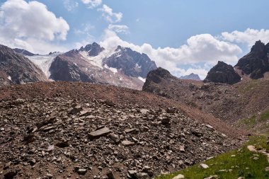 Morlar ve güneşli havada yeşil çayırlar arasındaki atmosferik manzara. Muazzam bir dağ manzarası, büyük bir buzulu ve dağ tepesi var. Moraine Kazakistan 'ın dağlık kesimlerinde. Karargah