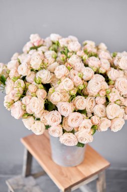 Alüminyum vazo ve çalılık gülleri. Çiçeklerle çiçekçi ilgileniyor. Elinde bir vazo çiçek olan bir kız yüksek kaliteli bir fotoğraf.