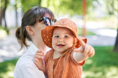 Genç anne ve 10 aylık akut bebek kızının portreleri. Güneşli bir yaz gününde çocuk parkında yürümek. Yüksek kalite fotoğraf