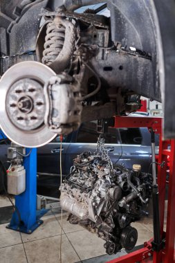 Bir araba tamircisi el feneriyle motoru inceliyor. Motor bloğu, özel vinç krikosuyla birlikte tamir masasında. Araba için teknik servis istasyonu yüksek kaliteli fotoğraf.