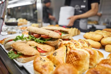 Taze sandviç, turta ve pizza bir kafe, açık büfe veya self-servis kafe vitrininde tercih edilebilir. Jambonlu ve peynirli kruvasan. Kafedeki rafta sıcak hamur işleri var. Çörekler dükkanda. Yüksek