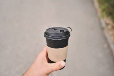 Bir adamın elinde sıcak bir bardak içki. Parkta bir adam elinde bir fincan kahve tutuyor. Kahvaltı hazırda bekliyor. Piknik ve dışarı çıkma konsepti yüksek kaliteli fotoğraf.