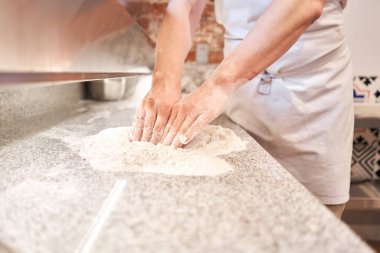 Şef pizza hazırlar. Çiğ pizza pişirmeye hazır. Mutfakta önlüklü aşçı pizza hamuru yapıyor. Arka planda yiyecek teslimatı için kutular. neopolitan