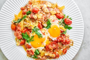 Kahvaltıda Shakshouka. Ev yapımı shakshuka, kızarmış yumurta, soğan, dolmalık biber, domates ve tavada maydanoz. Mermer arka plan. Üst Manzara. chakchouka. Yüksek kalite fotoğraf