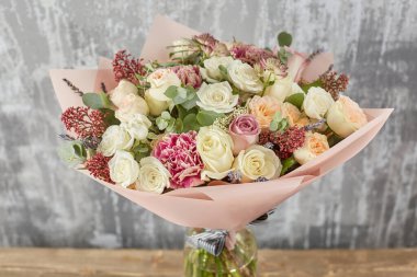 Kadının elinde küçük, güzel bir buket karışık çiçek. Çiçek dükkanı konsepti. Taze kesilmiş güzel bir buket. Çiçek teslimatı. Yüksek kalite fotoğraf