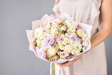 Kadının elinde küçük, güzel bir buket karışık çiçek. Çiçek dükkanı konsepti. Taze kesilmiş güzel bir buket. Çiçek teslimatı. Yüksek kalite fotoğraf
