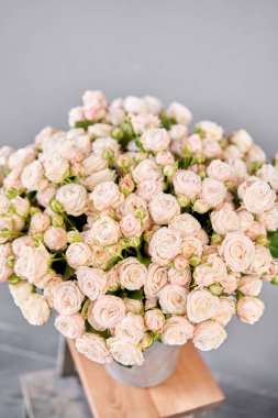 Alüminyum vazo ve çalılık gülleri. Çiçeklerle çiçekçi ilgileniyor. Elinde bir vazo çiçek olan bir kız yüksek kaliteli bir fotoğraf.