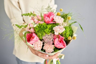 Dekor ambalajında güzel bir buket karışık çiçek. Kadın elinde güzel, taze bir buket. Küçük çiçekçi ve çiçek teslimatı.