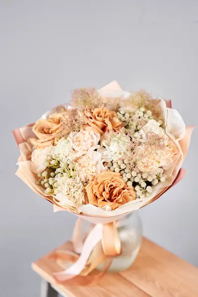 Beautiful bouquet of fresh flowers in glass vase on wooden table. A gift bouquet in mix color scheme for any holiday. The concept of a small flower shop. Flower and gift delivery.
