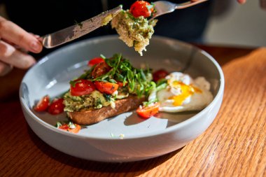 Nane aromalı brioche sandviç, roka ve vişneli domatesli haşlanmış yumurta. Sağlıklı kahvaltı. Tost, guacamole, sebze ve haşlanmış yumurta ve kremalı omlet..