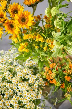 Bitkisel bitkilerden ve yıllık çiçeklerden oluşan sarı ve beyaz çiçeklerin renkli bir görüntüsü masanın üstünü süslüyor.