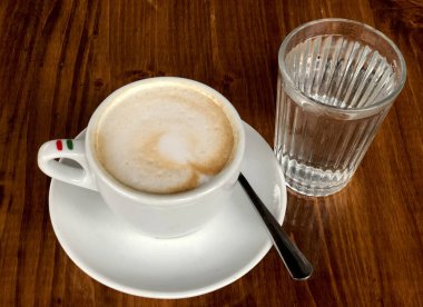 İtalyan kapuçino bardağı, kaşık ve ahşap bir masada bir bardak su. Yüksek kalite fotoğraf