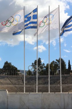 Olimpiyat Oyunlarının mirasını kucaklarken, Yunan ve Olimpiyat bayrakları orijinal Atina Olimpiyat Stadyumunun zemininde gururla dalgalanıyor.