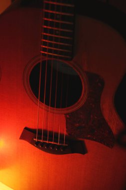 Çelik telli bir gitarın sıcak ışık ve yumuşak odak noktasıyla çekilmiş hatırlatıcı bir görüntüsü. Parıltı gitarın doğal ahşap yapısını arttırır. Müzikal ve sanatsal temalar için mükemmeldir..