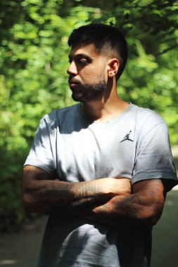 Zürih şehrinde güneşli bir günün tadını çıkaran, spor elbiseli dövmeli genç bir adamın canlı görüntüsü. Kentsel yaşam tarzı, fitness ve modern kültürle ilgili konular için mükemmel..