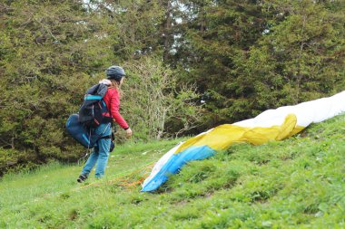 Dişi bir paraglider Güney Bavyera 'daki bir dağdan kalkmadan önce son hazırlıklarını tamamlar. Sahne, çarpıcı dağlık manzaranın ortasındaki heyecanı ve heyecanı yakalar..