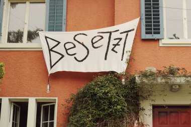 The facade of a squatted building in Zurich displays a bold Besetz banner, symbolizing the complex interplay of squatting, anarchy, and alternative lifestyles clipart