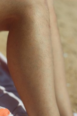 On a sun-drenched beach in Greece, a confident woman proudly displays her natural, hairy legs, embracing body positivity and challenging societal norms. clipart